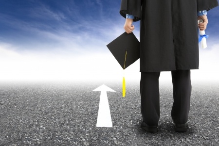 Image of a graduate standing on the road and forward arrow